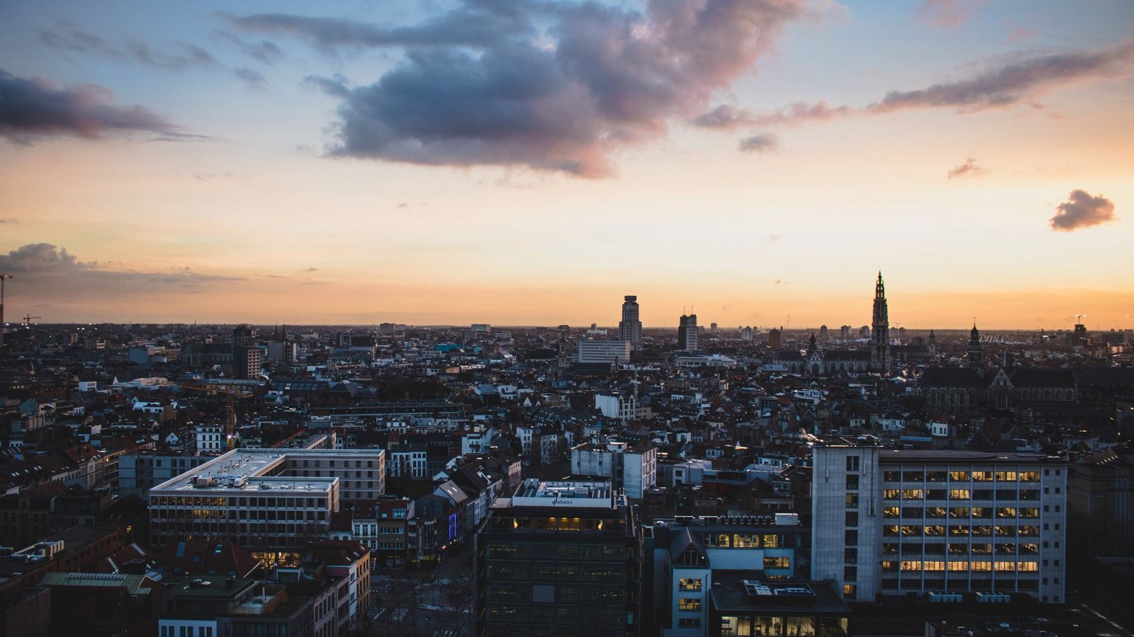 Antwerp seen from above at dusk, its cathedral spire rising over the rooftops.
