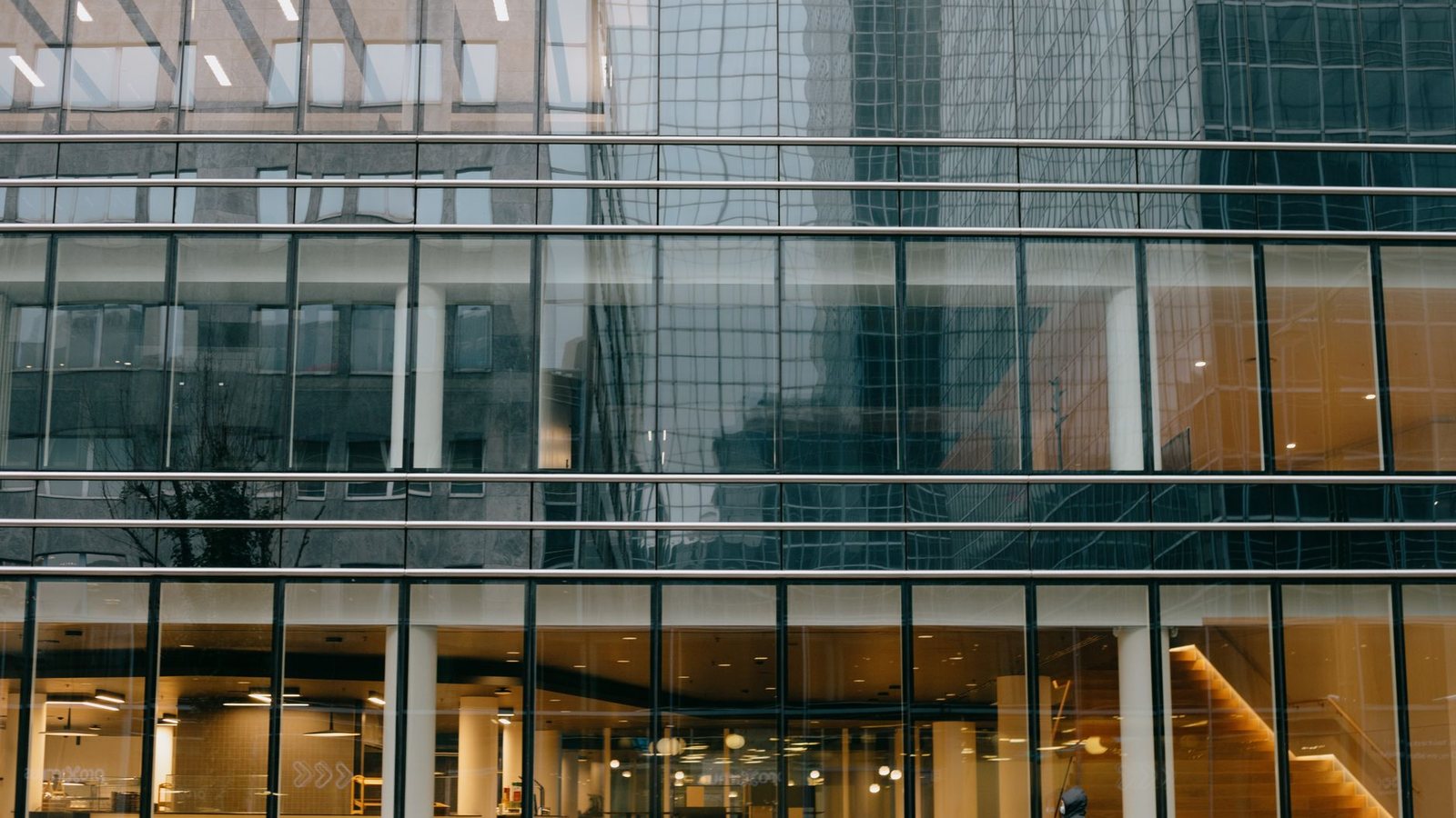 The contemporary glass facade of an office building in Brussels reflecting the surrounding architecture.
