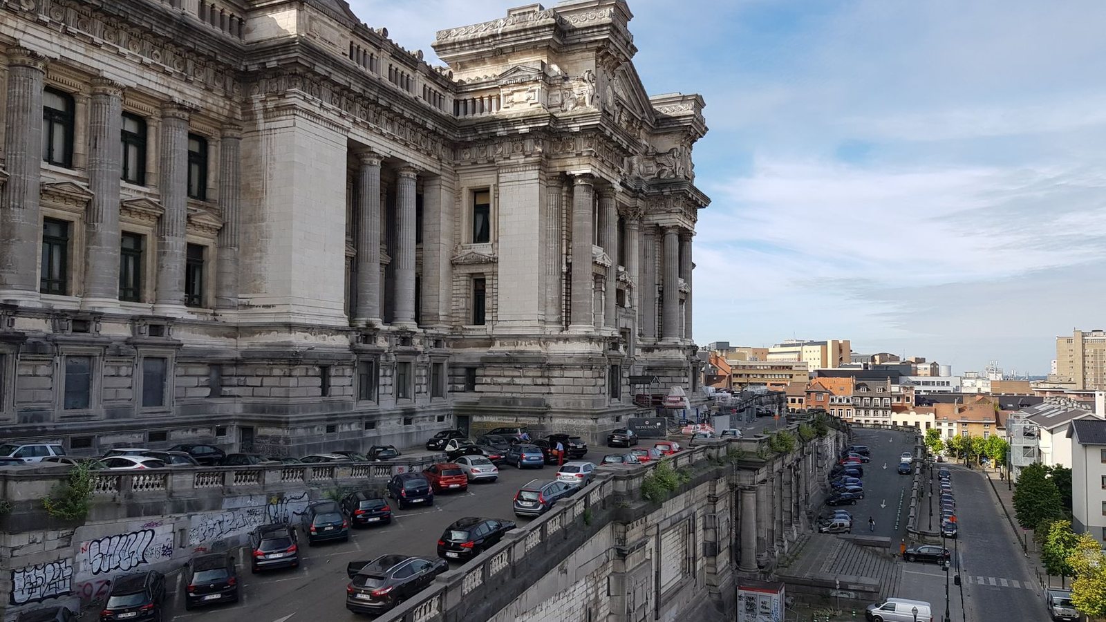 View of Brussels' iconic Palais de Justice with parked cars and urban landscape.