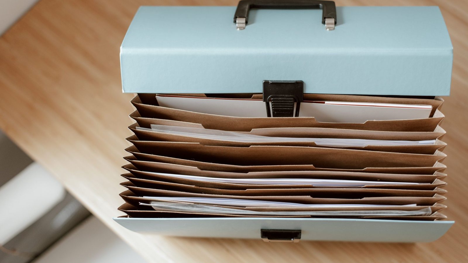 A document case and loose papers laid out on a wooden table, the kind of file a Belgian company change is prepared from.