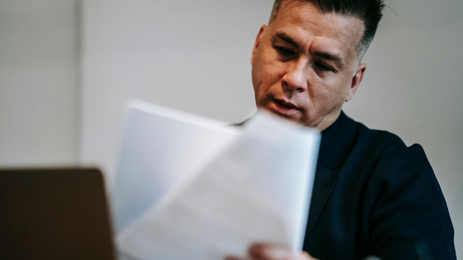 A man at a desk working through printed paperwork, the document review an application file takes.