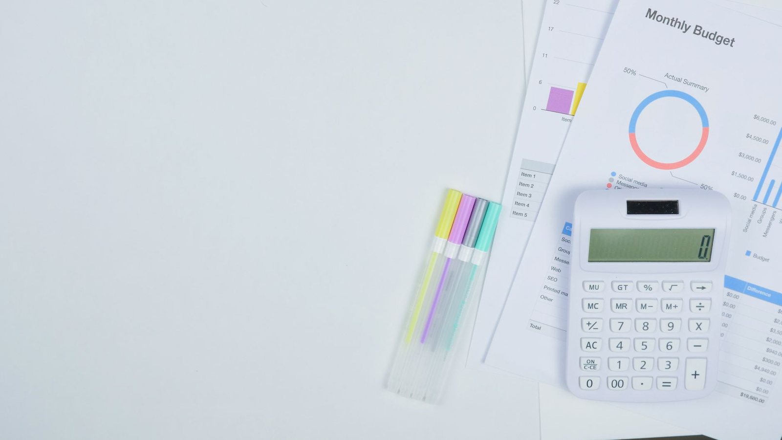 A calculator resting on printed budget sheets with coloured index tabs and charts.